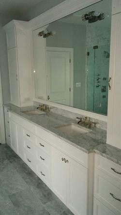 Double vanity with white custom cabinetry below and large mirror above