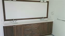 Double vanity in dark wood color with framed matching mirror above