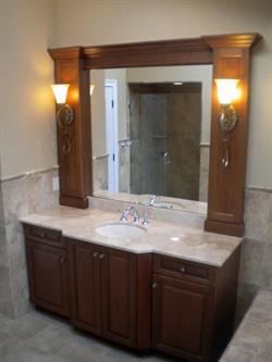 Sink with dark wood vanity storage and sconce lighting beside mirror