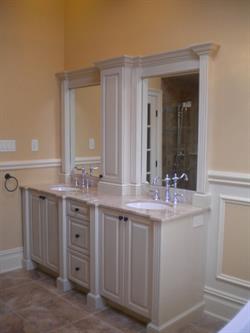 Yellow and white bathroom with double sinks and white vanity storage below