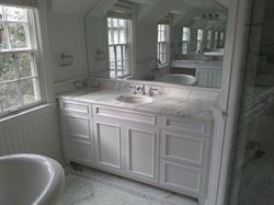White bathroom with large mirror and white vanity storage below