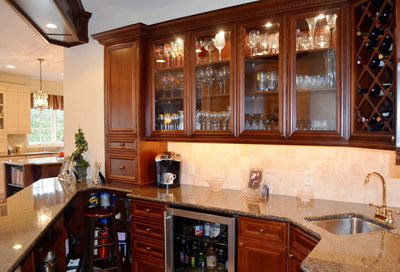C-shaped home bar with lighted glass cabinets, sink, and under counter storage