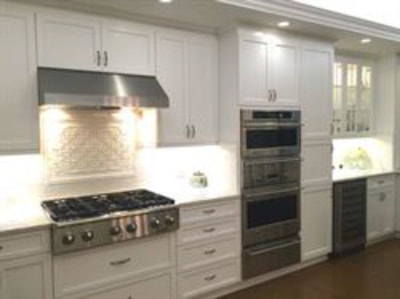 White kitchen with stainless steel appliances and decorative backsplash