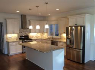 White kitchen with tiled backsplash and lighting over dining island