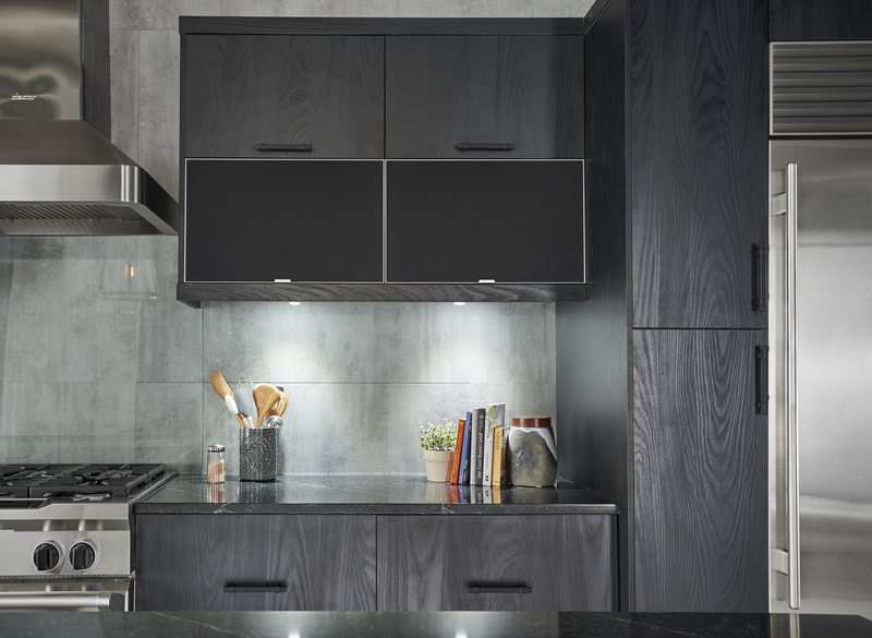 Closeup of black and gray kitchen, under cabinet lighting